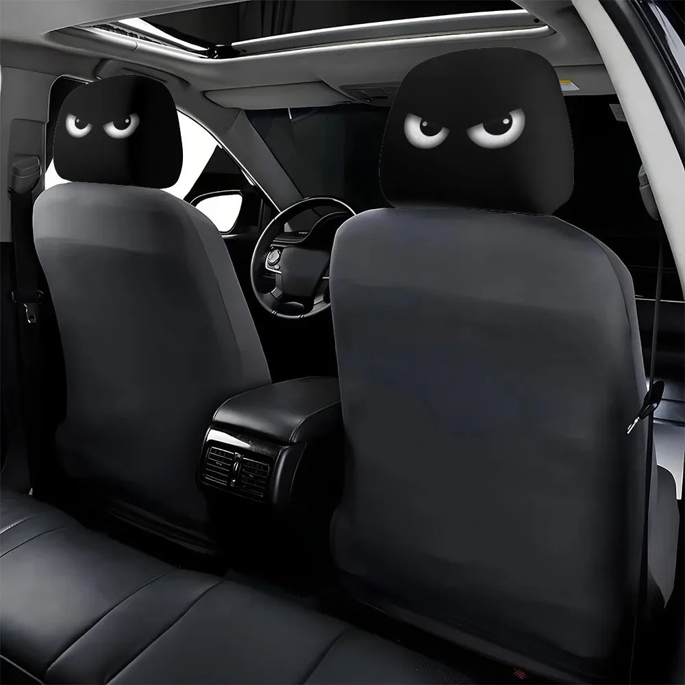 Two black car headrest covers with funny slanted eyes are shown inside a vehicle cabin.