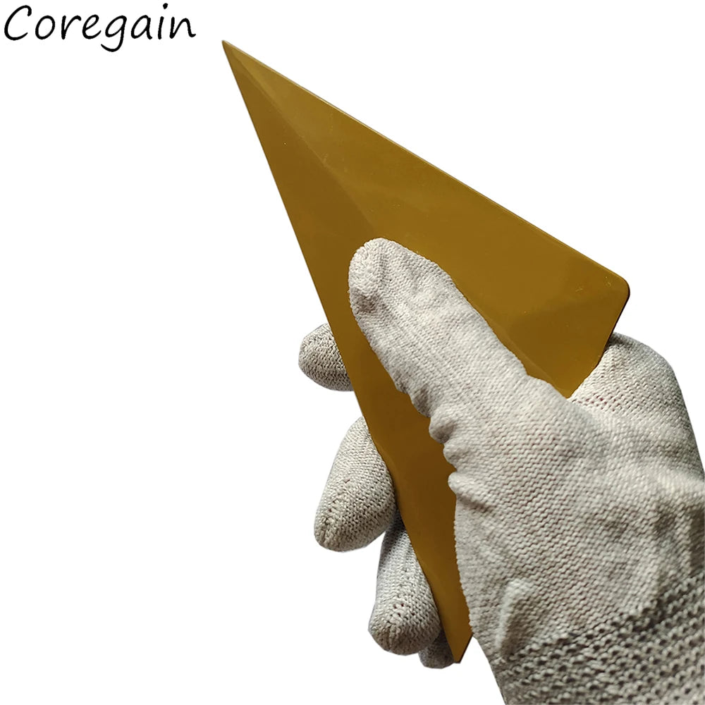 A hand wearing a light-colored glove holds a golden yellow triangle shaped squeegee tool.
