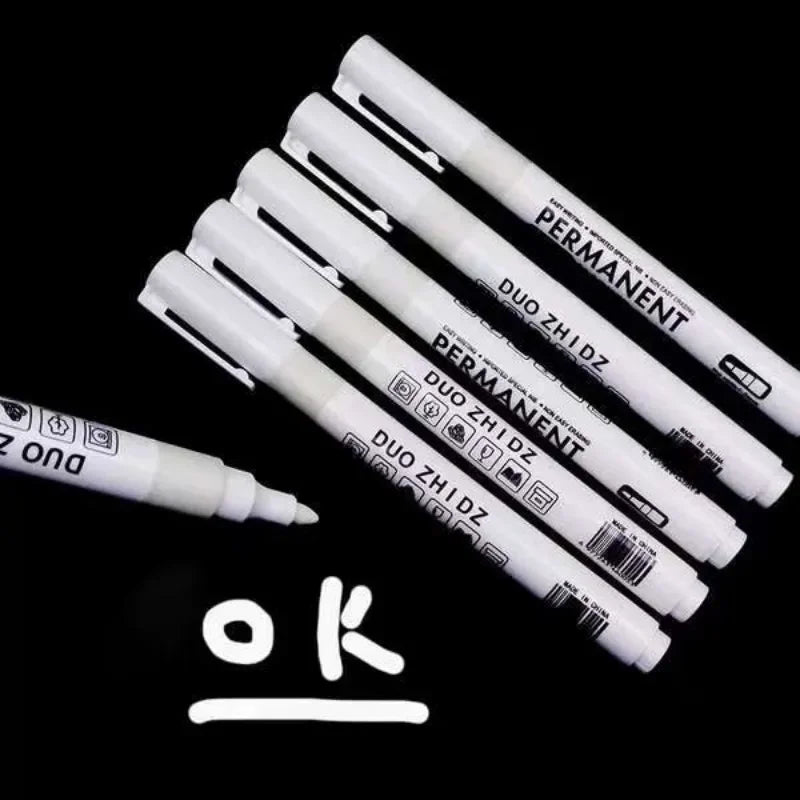 A set of black and white waterproof permanent paint markers is displayed diagonally on a black background.
