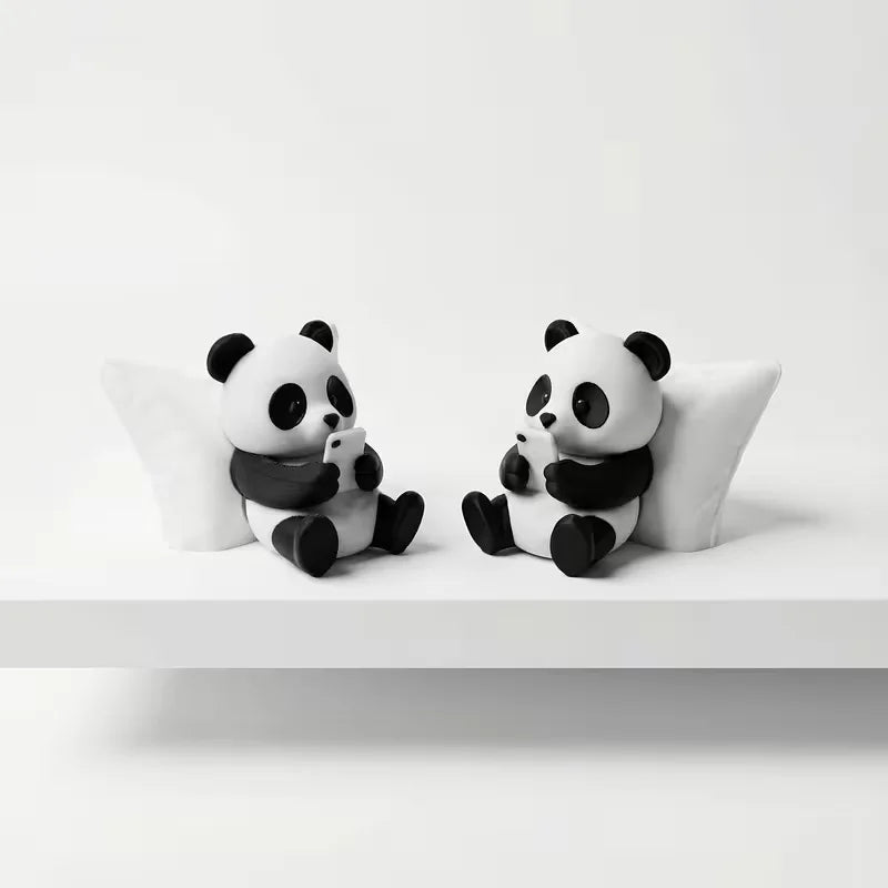 A pair of cute panda sculpture desk ornaments sitting on a white surface.
