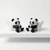 A pair of cute panda sculpture desk ornaments sitting on a white surface.