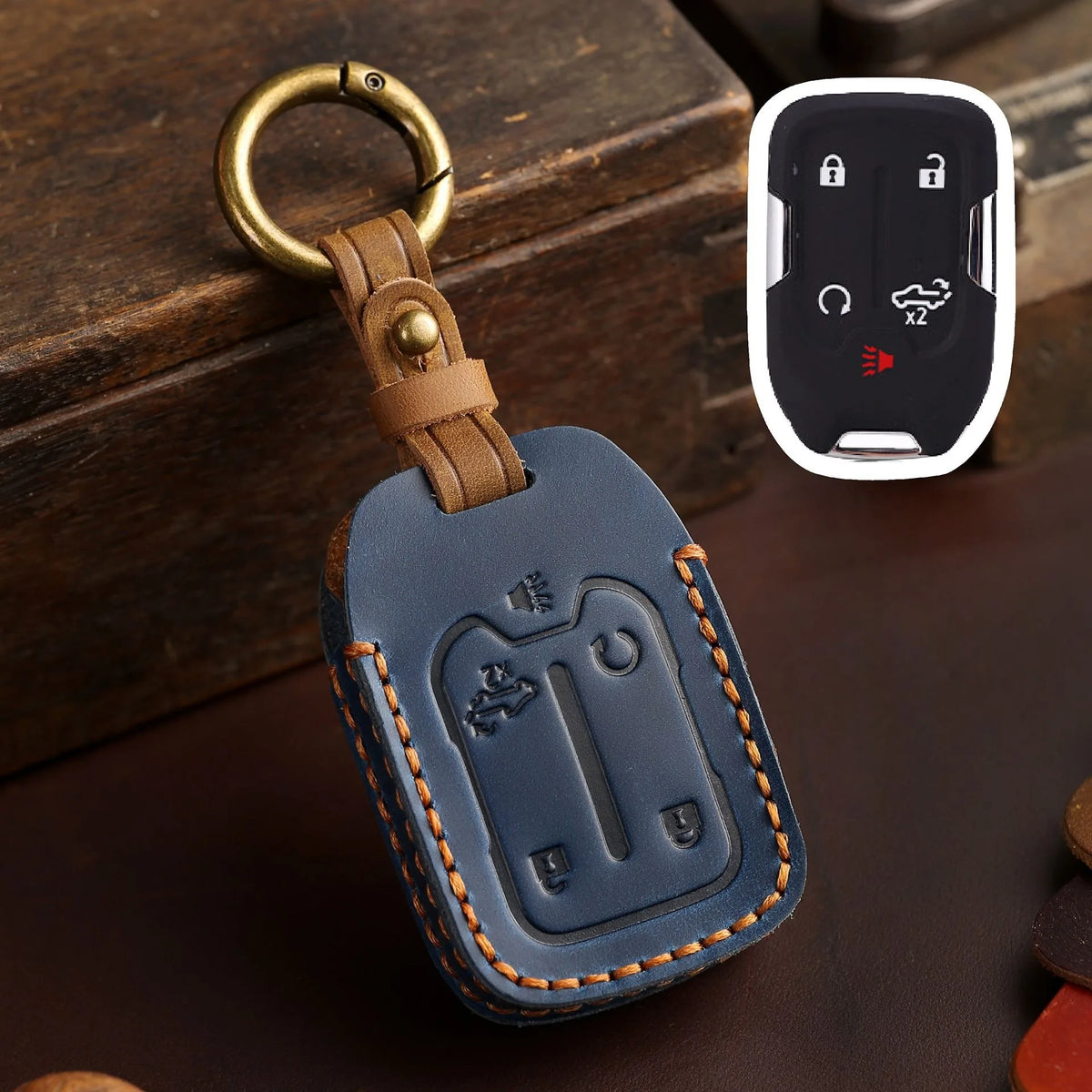 A dark blue leather key cover with a brass ring attached, featuring cutouts for Chevrolet and GMC truck keys.