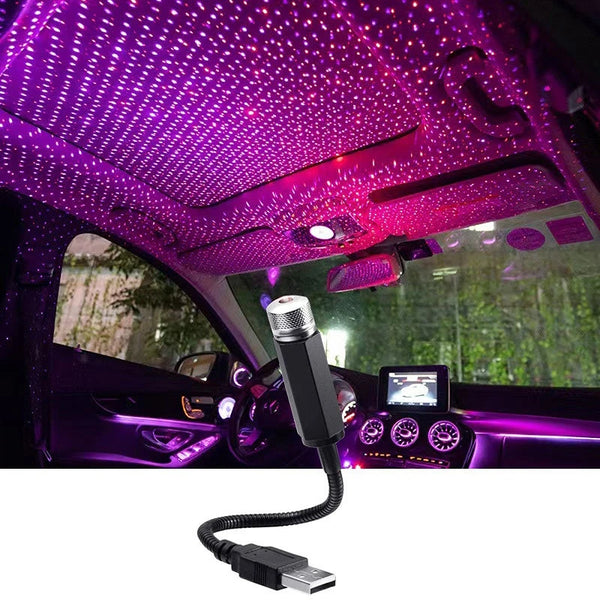 An LED starry sky projector is mounted in a car interior, casting purple lights onto the ceiling and surrounding area.