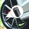 Close-up view of an American flag aluminum tire valve cap with a textured finish mounted on a wheel rim.