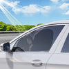 A white car's side window with a sunshade curtain installed, showing sunlight rays and a blue sky.