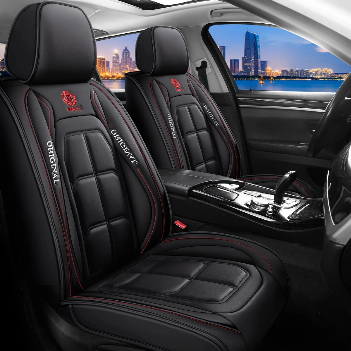 Interior view of a car showing black leather seat covers with red stitching and embossed branding.