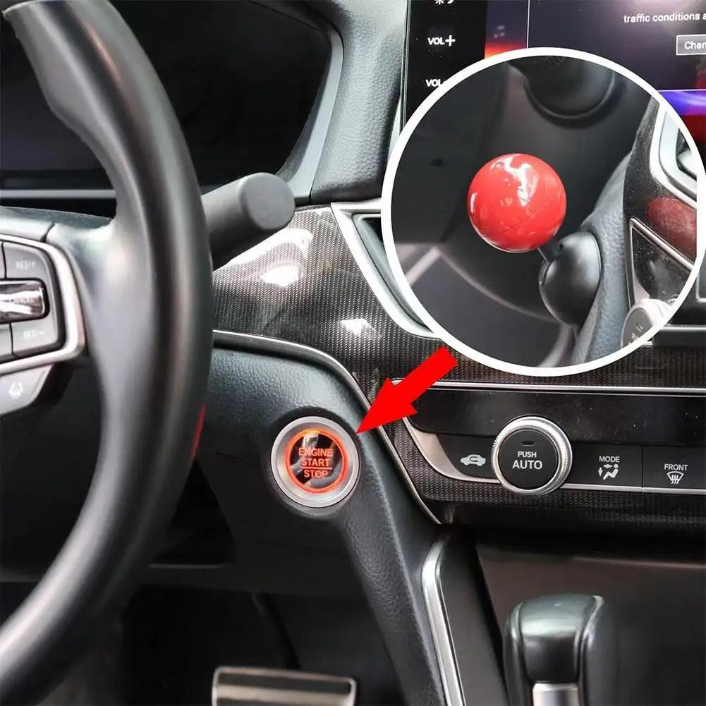 Close-up of a red push start ignition button cover on a car steering wheel dashboard.