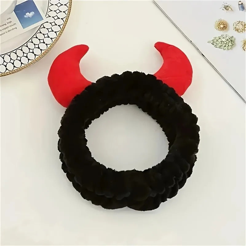 Bandeau en corne de diable noir et duveteux avec accents rouges sur une surface blanche.
