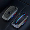 Un juego de fundas para llaves de coche de fibra de carbono negra, incluyendo una funda principal y un mando a distancia.