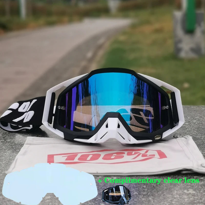 A pair of white and black motocross goggles with clear lenses resting on a cloth, featuring a red 106% logo.