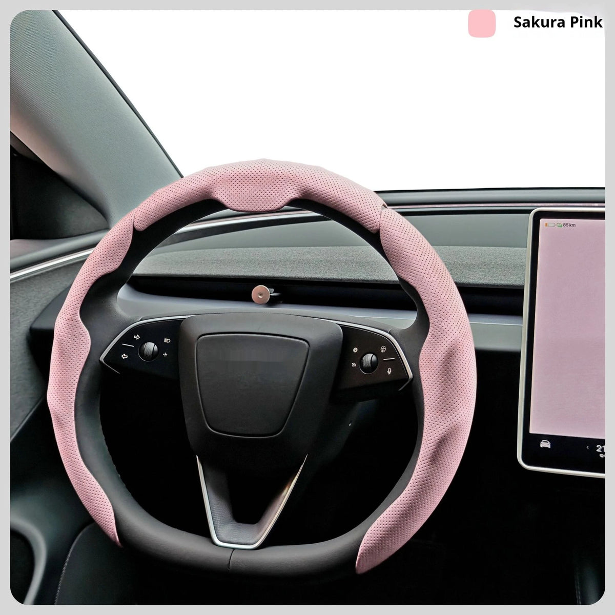 A pink steering wheel cover is shown in a car interior, featuring a leather-wrapped rim and controls.