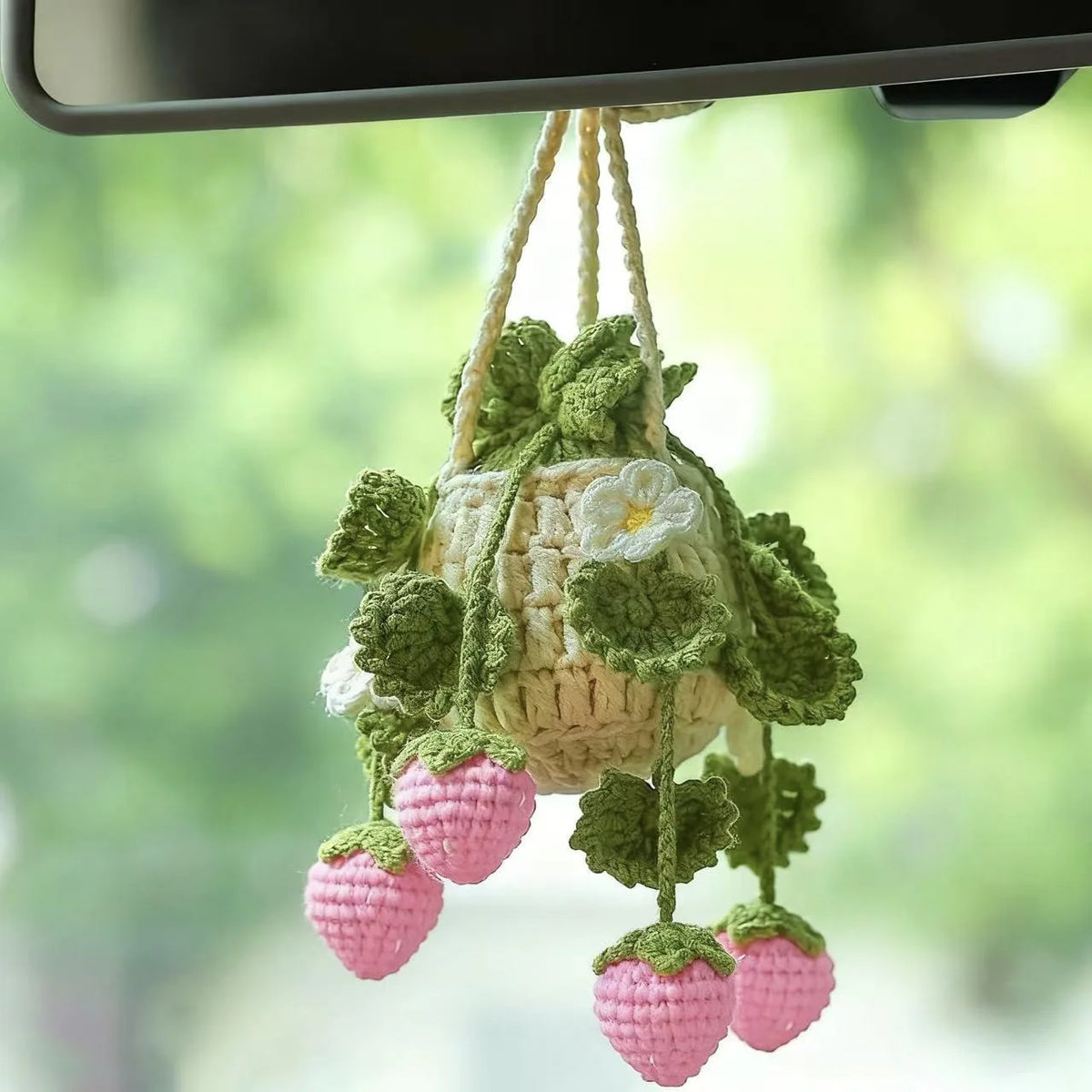 A handmade strawberry crochet hanging decor featuring pink strawberries and green leaves.