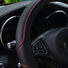 Close-up view of a black embossed leather steering wheel cover with red stitching and controls.