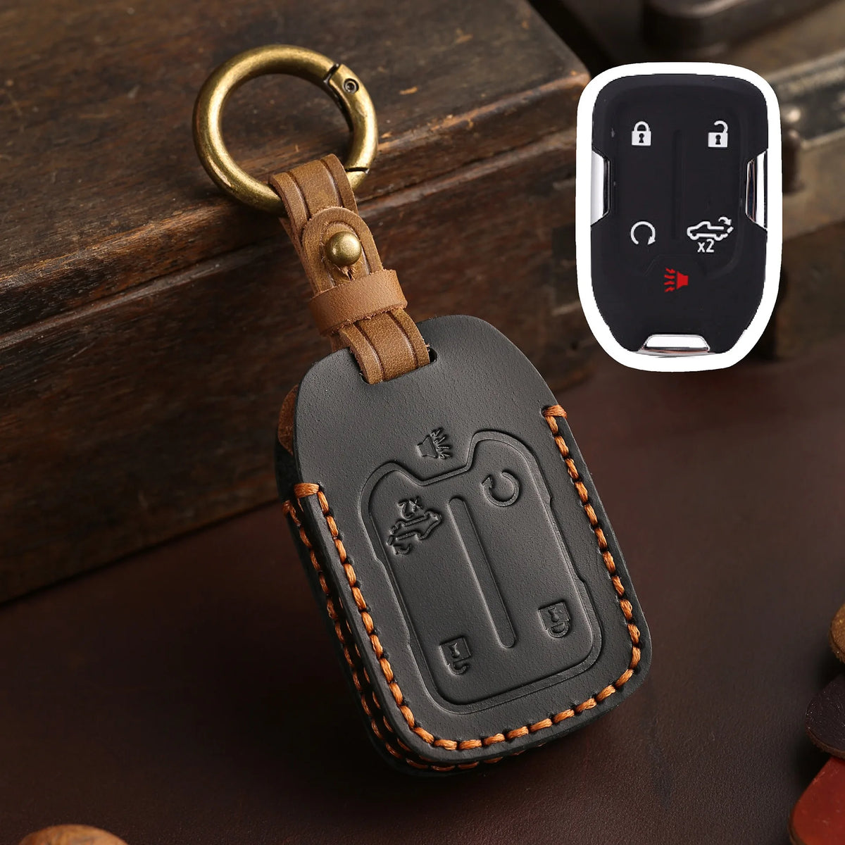 A brown leather key cover with a brass ring and a white electronic key fob is shown on a dark surface.