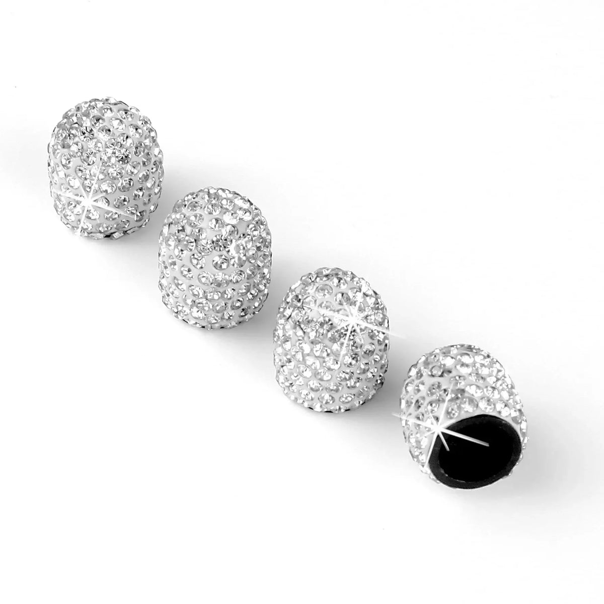 Eine Reihe von vier klaren Diamant-besetzten Felgbdeckkappen für Autoreifen.