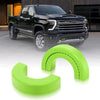 A black pickup truck is shown with bright lime green silicone tow hitch covers lying next to it.