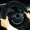 A hand grips a black winter plush steering wheel cover inside a car