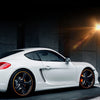 A white sports car with orange rim protectors parked on a dark surface.