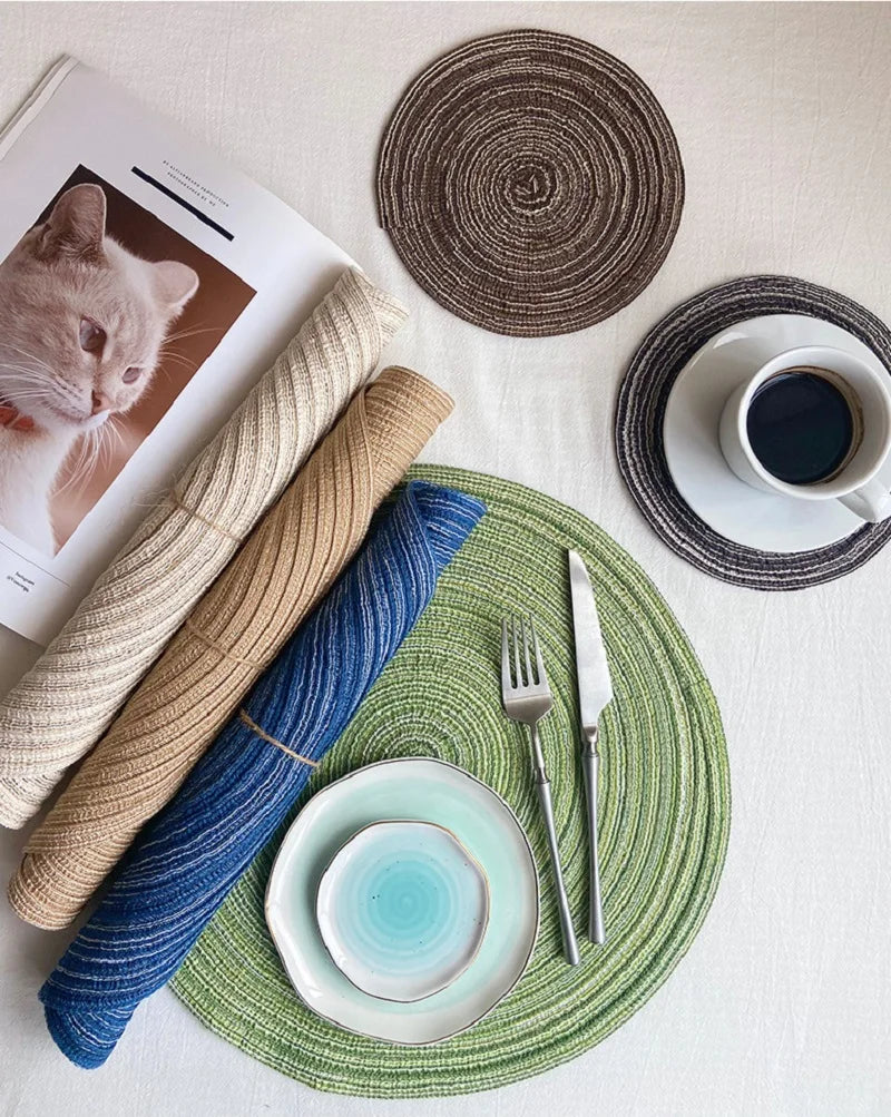 Un ensemble de dessous-de-verre et de sets à couverts tressés aux couleurs beige, bleu et vert naturels.
