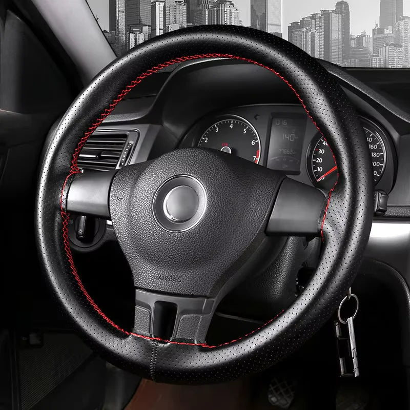 A close-up view of a black steering wheel with red stitching and an analog instrument cluster in a car interior.