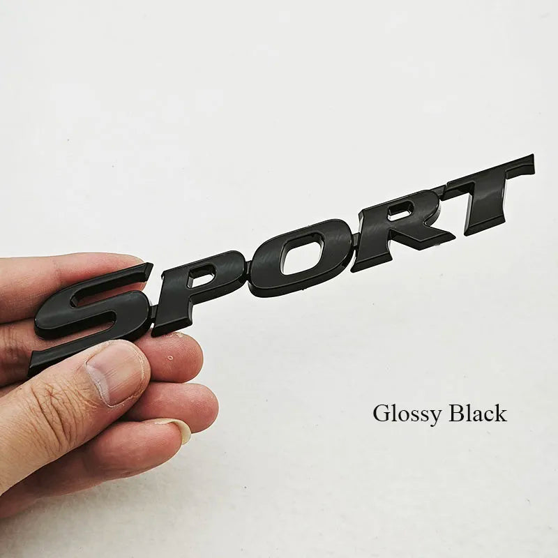 Glossy black 3D chrome car logo emblem for rear trunk being held by a hand