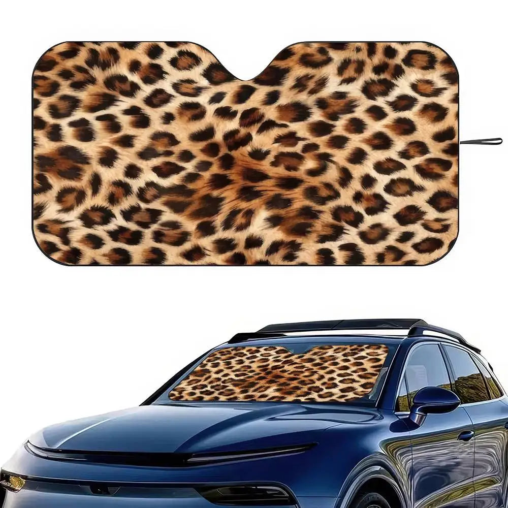 A leopard print car sunshade is shown placed on the windshield of a blue car.