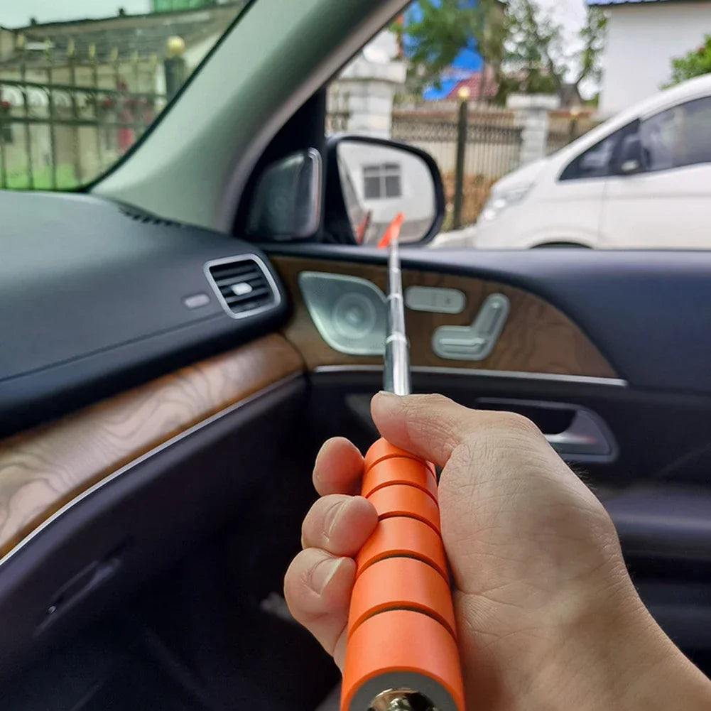 A hand holds an orange telescopic window squeegee, positioned inside a car's interior.