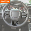 A close-up view of a steering wheel with a leather wrap and decorative carbon fiber accents.