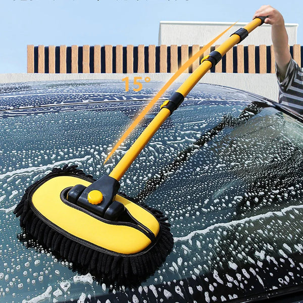 A yellow telescoping car wash mop is being used to clean water spots off a dark car's windshield.