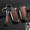 A black aluminum alloy key fob cover with a leather strap and keyring is shown against a dark background.