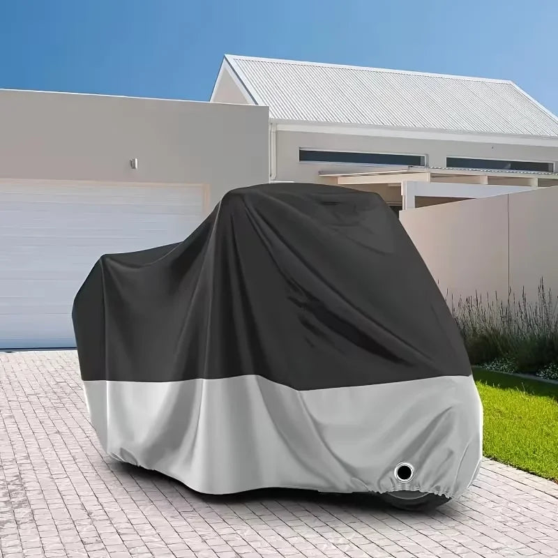 A black and white universal motorcycle protective cover lying on a paved driveway.