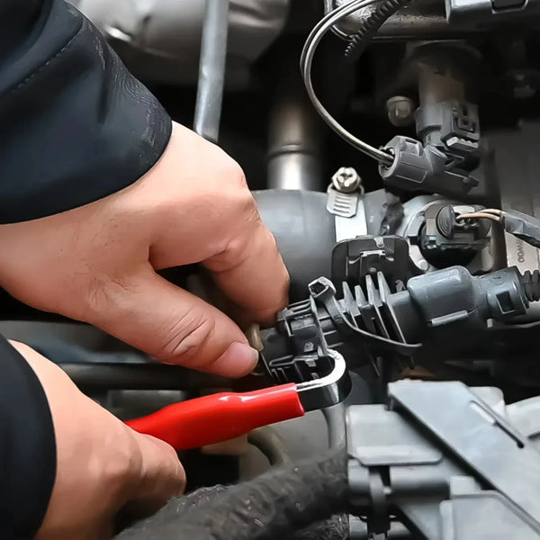 A hand uses a red electrical terminal removal tool to disconnect a connector on a mechanical system.