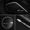 Close-up view of black 3D aluminum Chevrolet audio emblems on a vehicle interior panel.