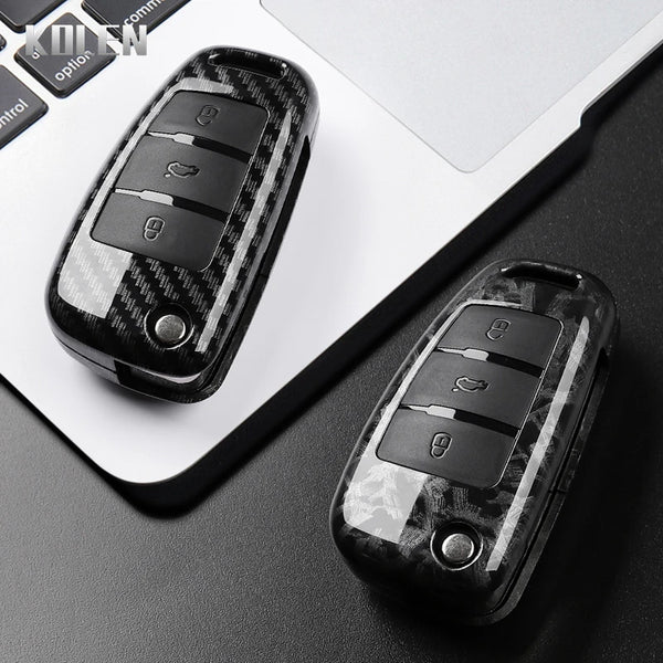 A close-up view of a black carbon fiber car key case cover resting on a laptop keyboard.