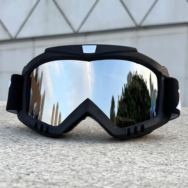 A pair of black windproof sports goggles with reflective lenses resting on a gray surface.