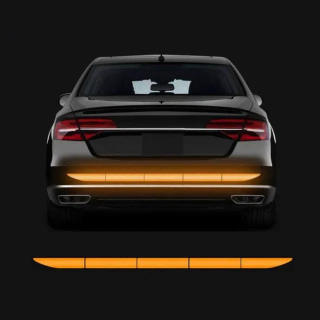 Rückansicht eines schwarzen Autos mit reflektierenden Sicherheitsstreifen am unteren Stoßfänger.