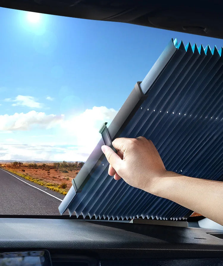Une main ajuste un pare-soleil rétractable bleu pour le pare-brise d'une voiture pour la protection UV.