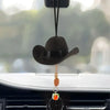 A black cowboy hat ornament with a gold chain hanging from it, displayed on a car interior.