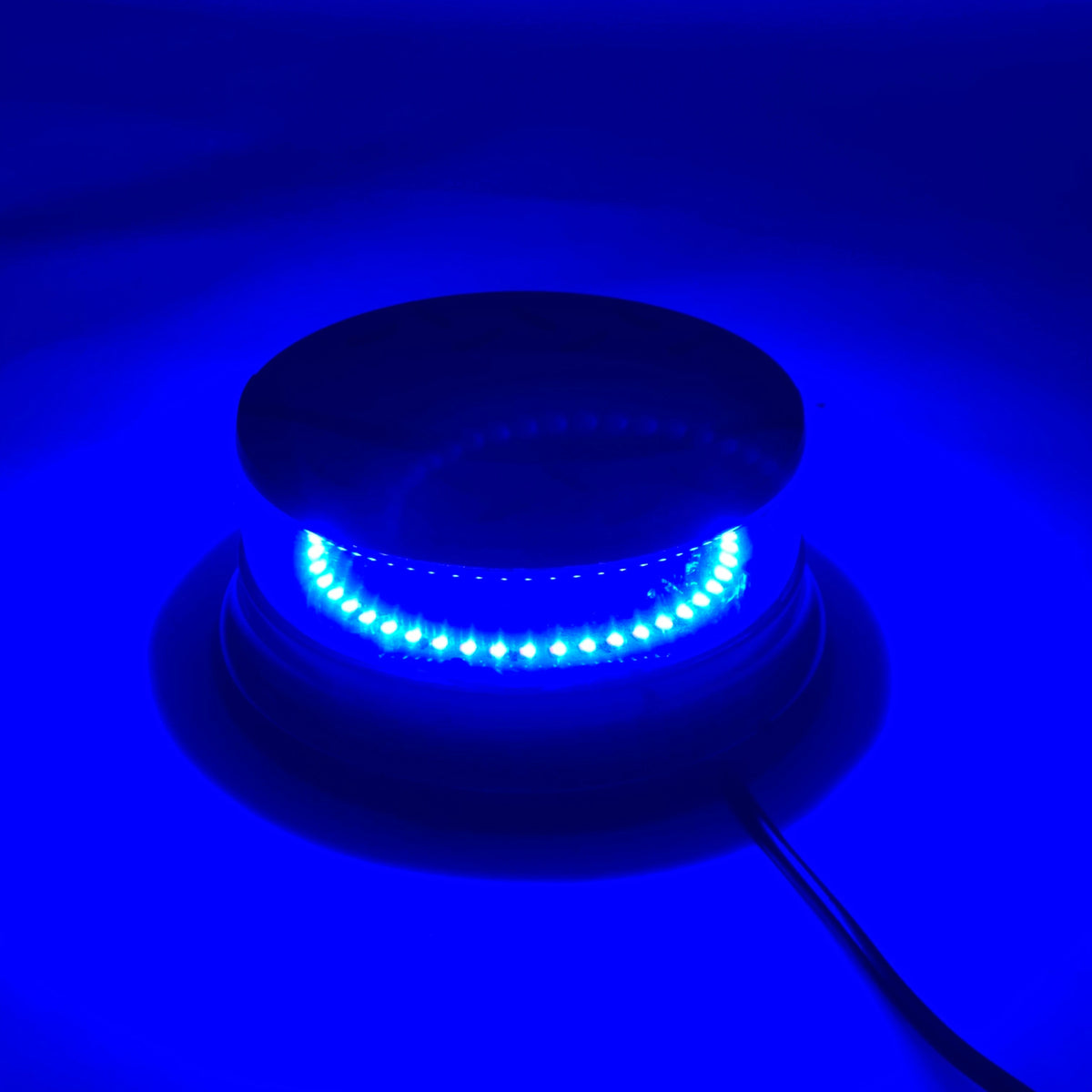 An emergency LED strobe light is shown mounted on a dark surface, emitting bright blue light.