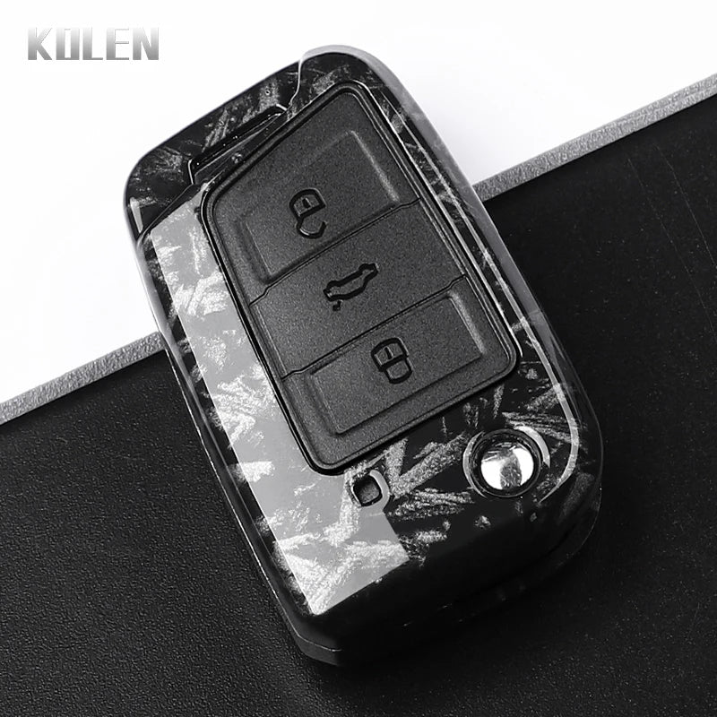 A black carbon fiber button cover for a car key, showing the electronic buttons.