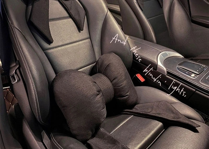 Un oreiller de cou noir à accent est placé sur le dossier d'un siège de voiture, avec du texte manuscrit visible à proximité.