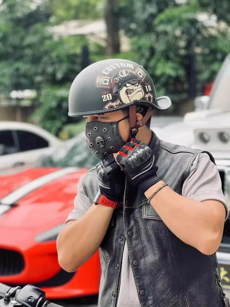 Eine Person mit Custom-Motorradhelm und schwarzen Lederhandschuhen ist draußen in der Nähe eines roten Sportwagens zu sehen.