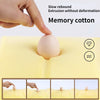 Hand pressing a soft, beige memory cotton object into a yellow foam surface demonstrating slow rebound extrusion.