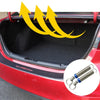Intérieur du coffre d'une voiture rouge montrant un mécanisme de levage à ressort pour le coffre automatique.