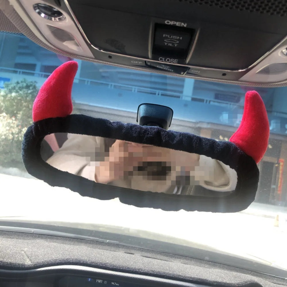 A red and black cartoon plush cover is placed over a car's rearview mirror.