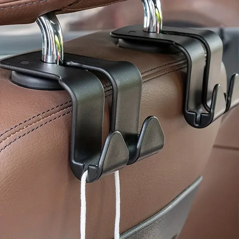 A close-up of black headrest hooks attached to a brown leather car seat.