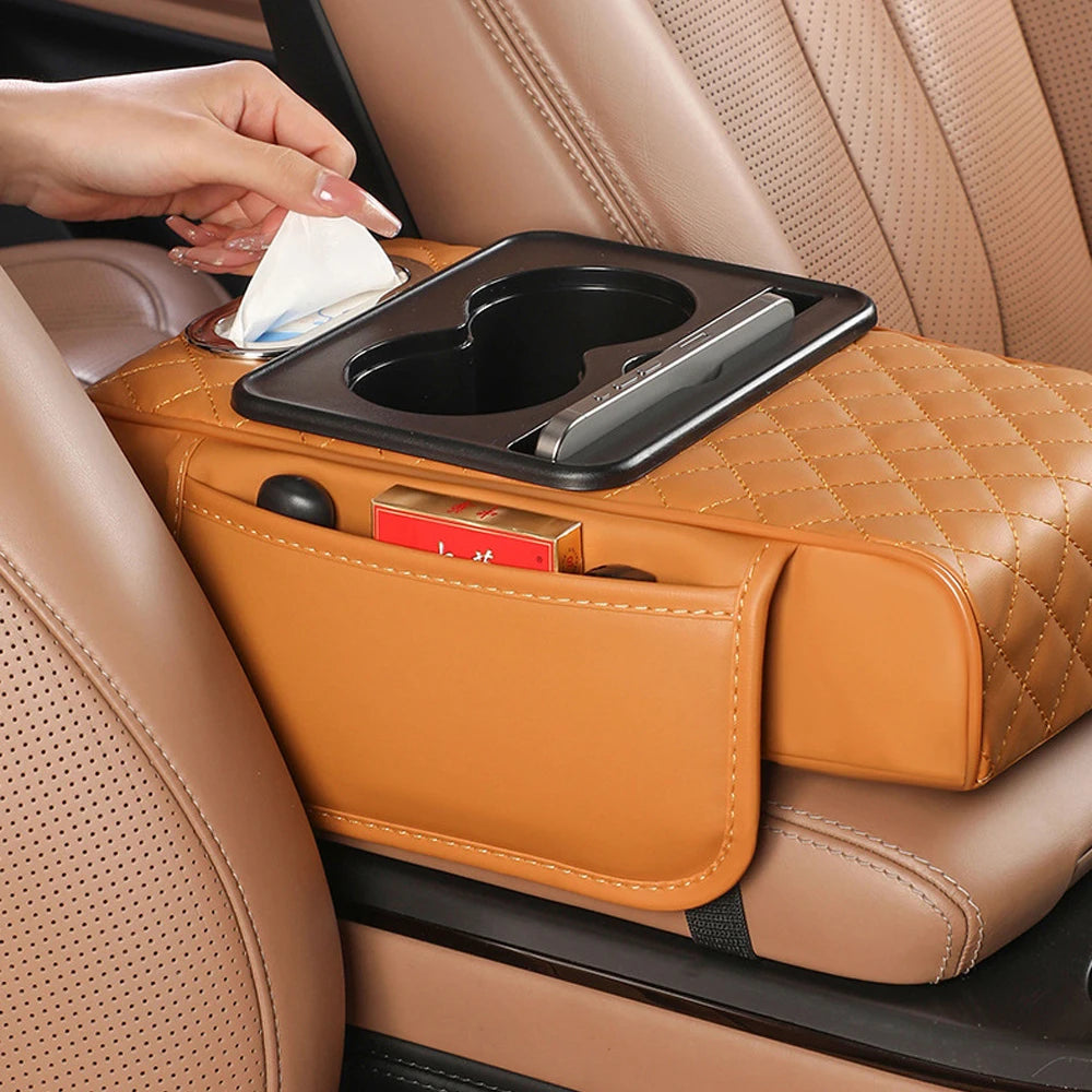 A hand places a tissue in the holder of an orange quilted car armrest cushion.