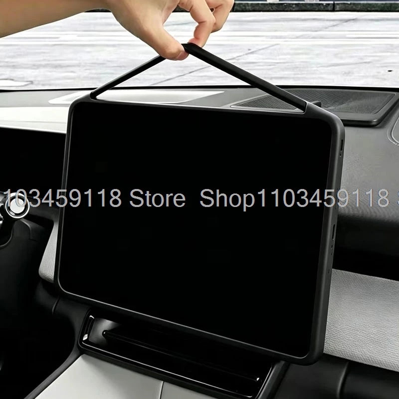 A hand is placing a silicone screen frame protector onto a car display screen.