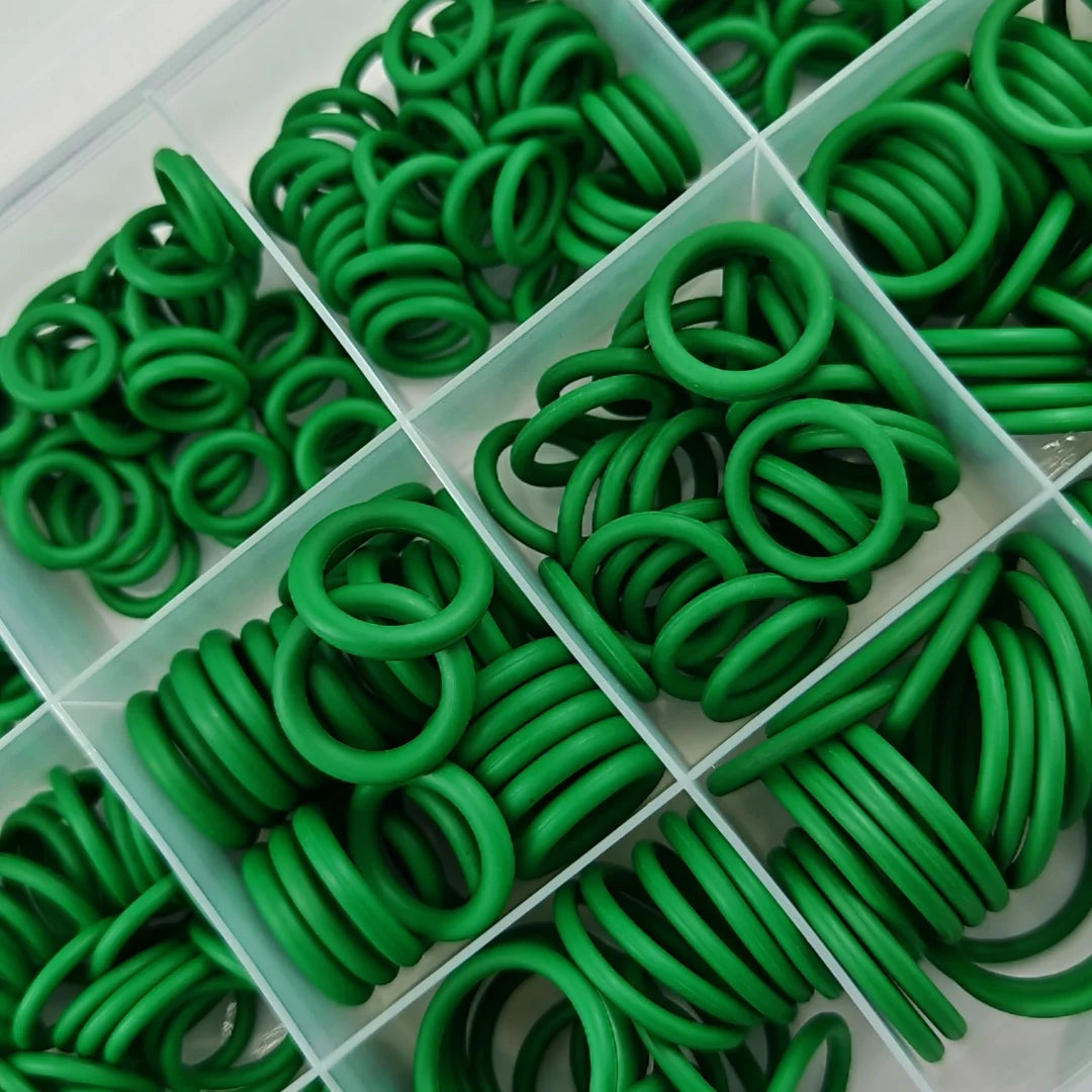 A collection of green rubber O-rings and gaskets arranged in a clear plastic tray.
