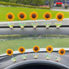 Une rangée d'ornements de tournesols jaunes et oranges sur la console d'une voiture.